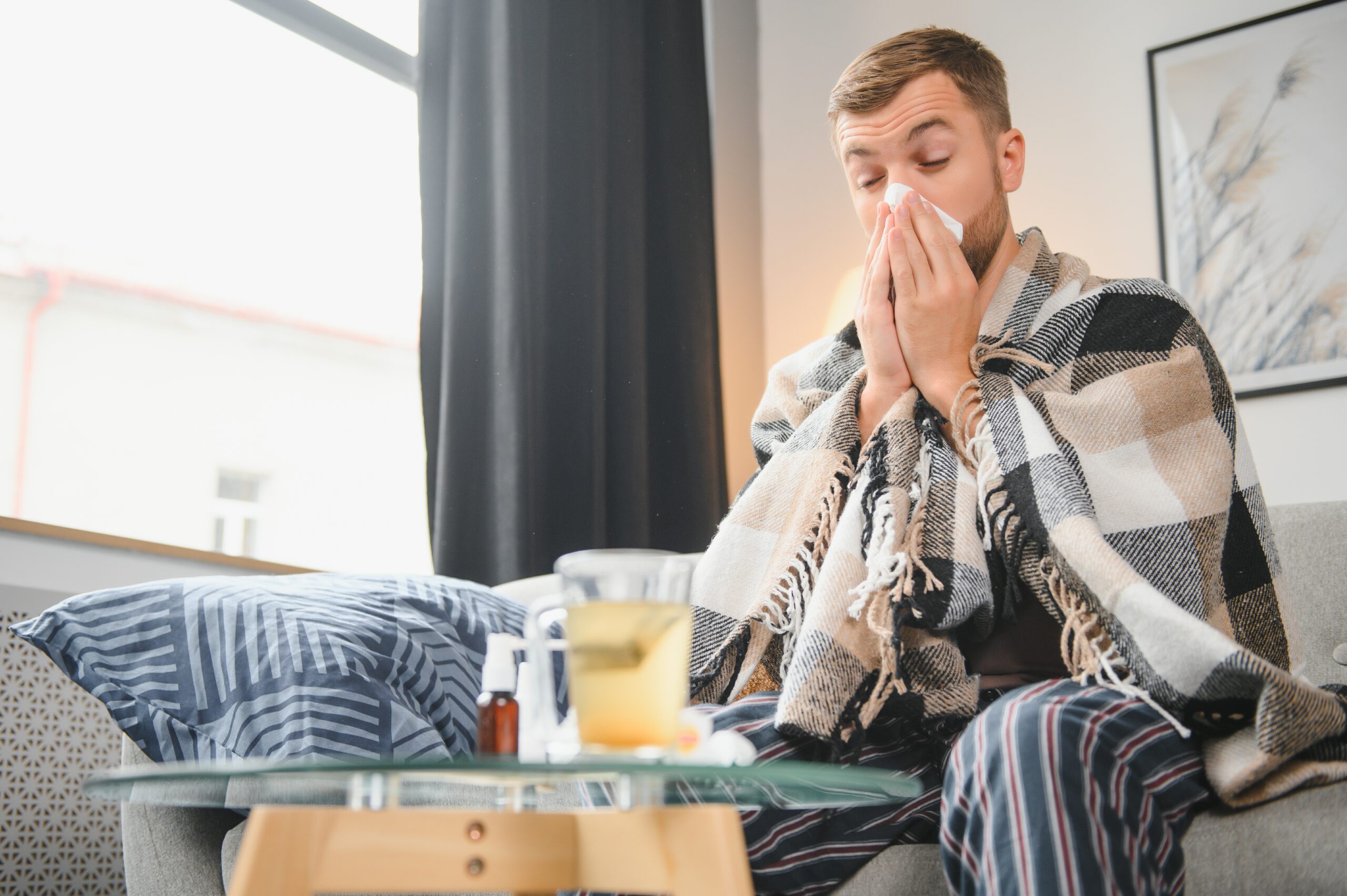 Sick Man On Sofa At Home And Blowing Nose